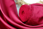 A close-up view of a vibrant red fabric, possibly silk or satin, with a rolled-up end visible.