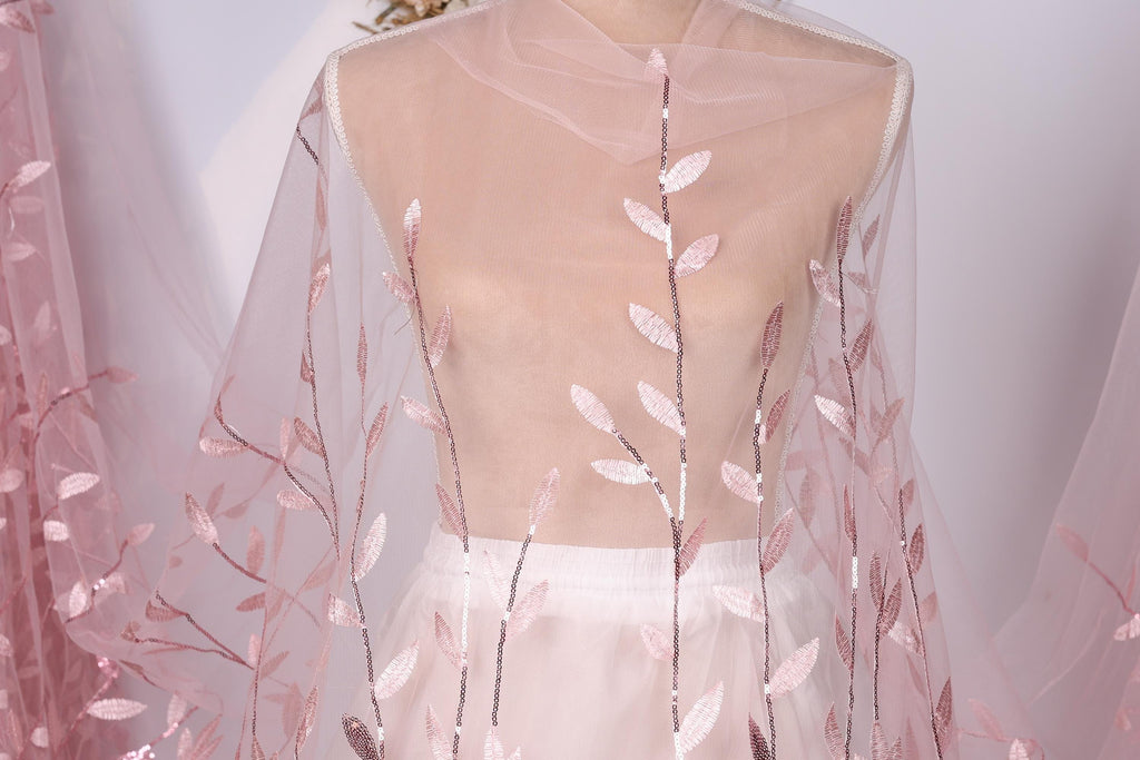 A mannequin wearing a sheer pink fabric with delicate pink leaf patterns.