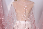 A mannequin wearing a sheer pink fabric with delicate pink leaf patterns.