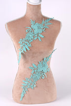A mannequin torso with a decorative floral lace piece attached to it.