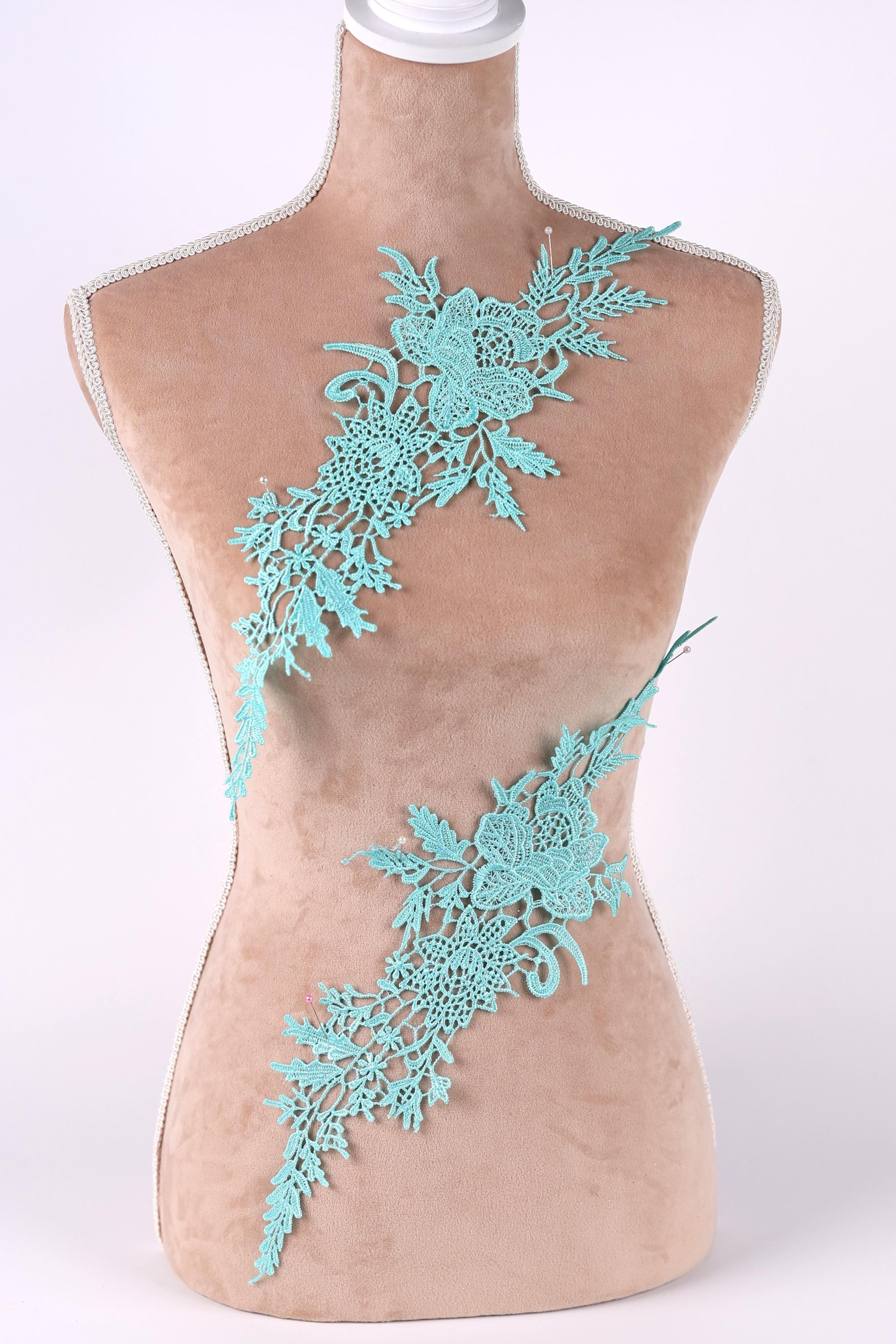 A mannequin torso with a decorative floral lace piece attached to it.