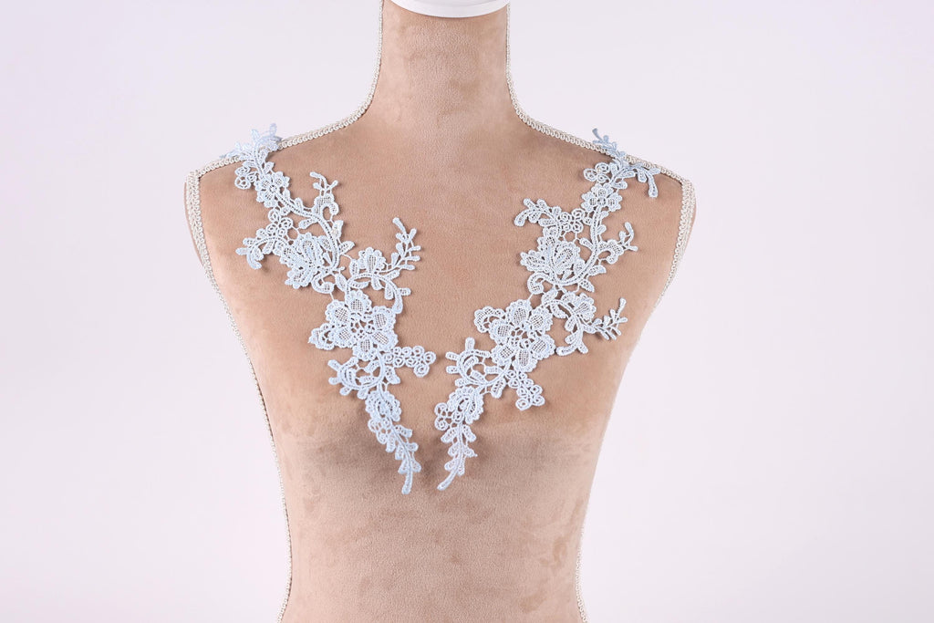 A mannequin wearing a white lace necktie with intricate floral patterns.