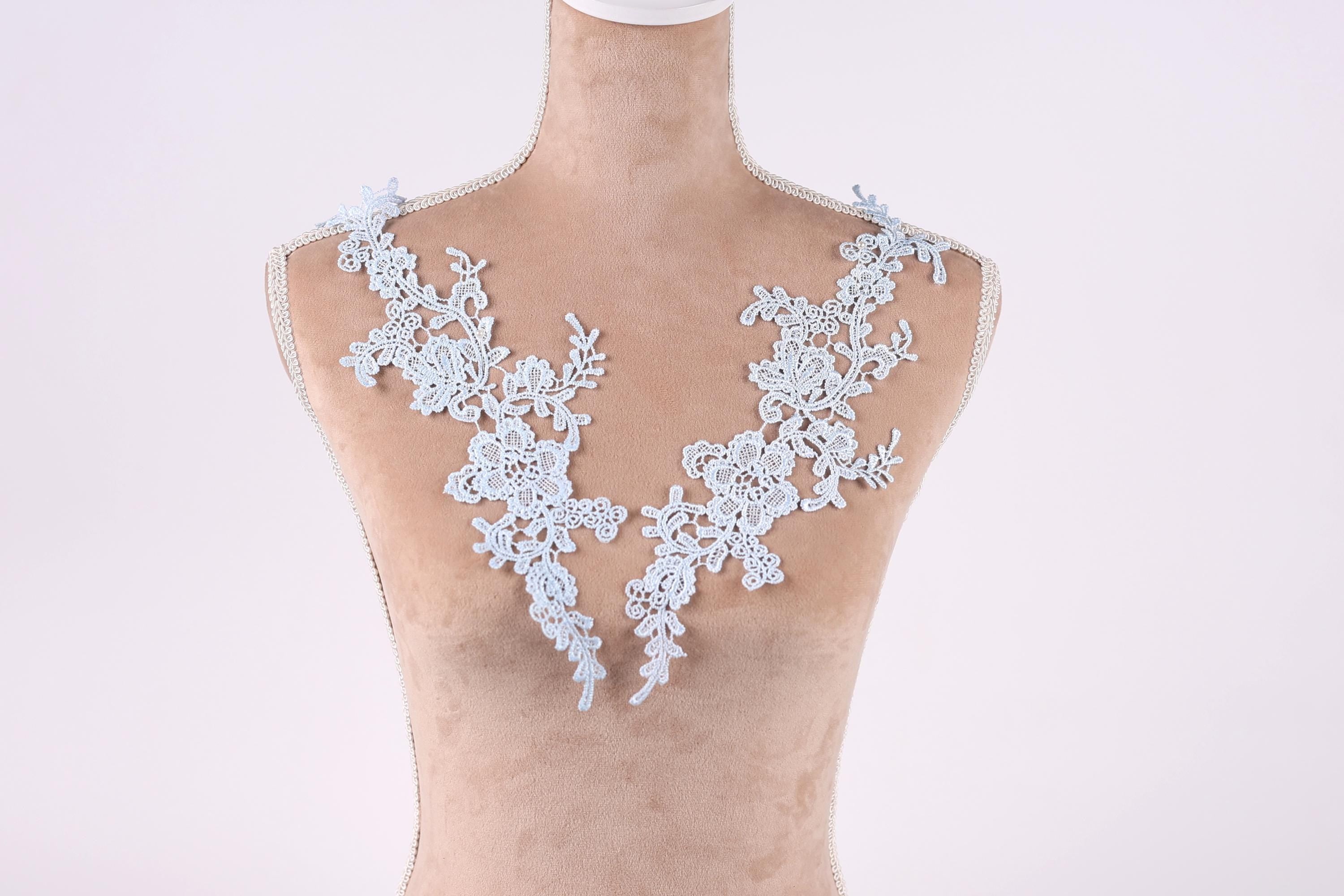 A mannequin wearing a white lace necktie with intricate floral patterns.