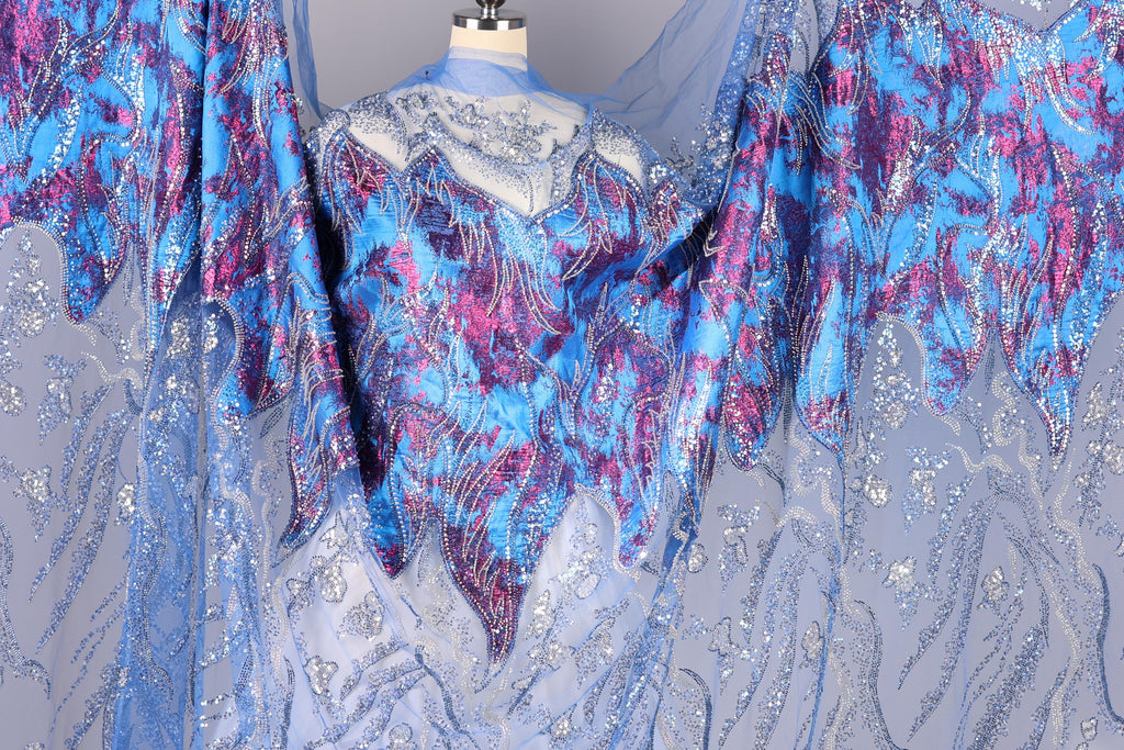 a mannequin wearing a blue and purple patterned dress with sequins and lace details.
