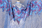 a mannequin wearing a blue and purple patterned dress with sequins and lace details.