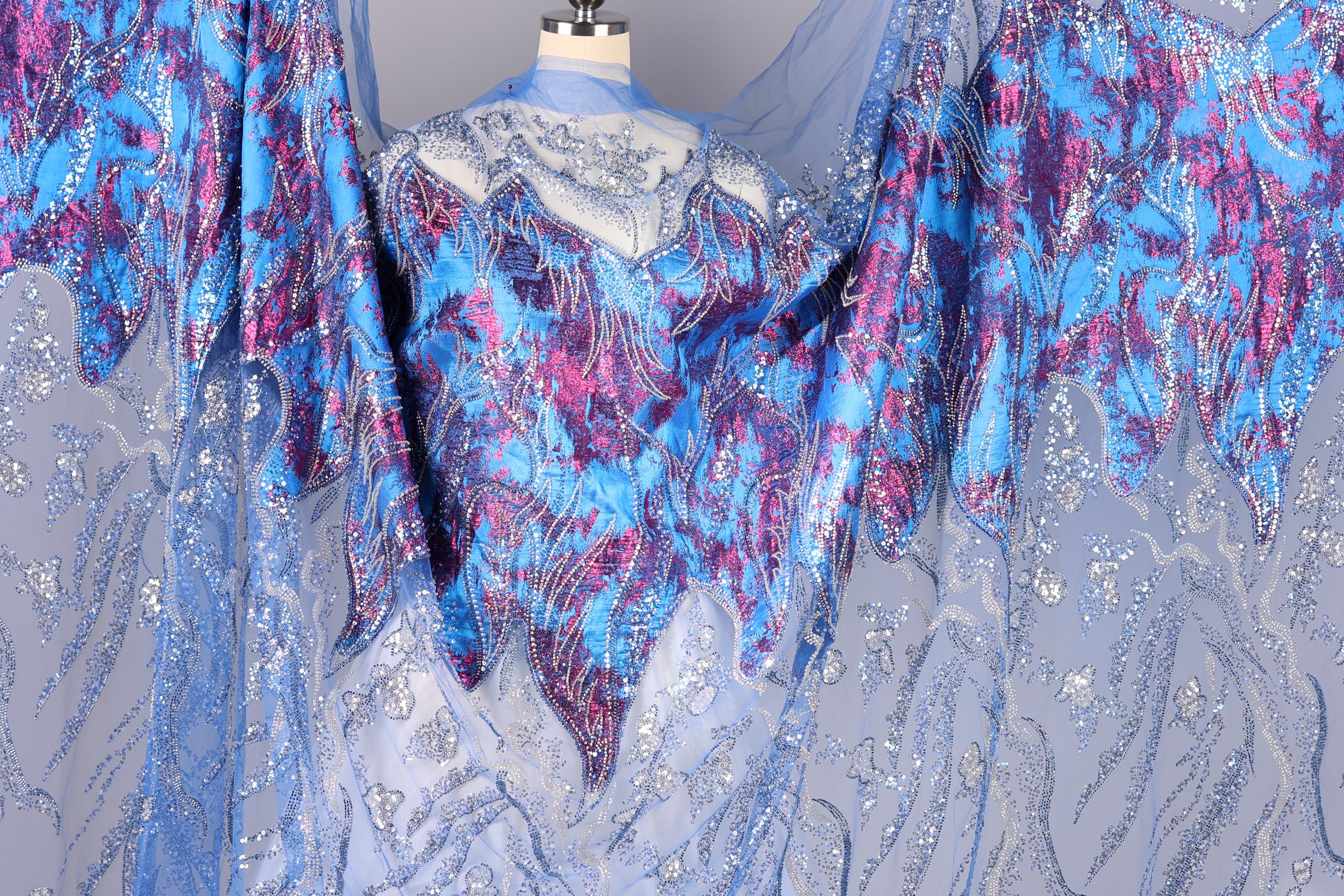 a mannequin wearing a blue and purple patterned dress with sequins and lace details.