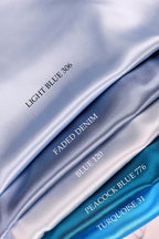 a close-up view of four different colored satin fabrics, each with a label indicating the color and the name of the fabric.