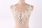 A mannequin wearing a white lace dress with intricate floral patterns.