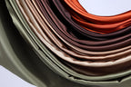 A close-up view of a pile of colorful fabric, including shades of green, brown, and orange, arranged in a visually appealing manner.