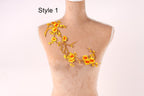 A mannequin with a decorative embroidered design on its shoulder, featuring yellow flowers and branches.