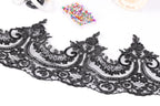 a close-up view of a black lace trim with intricate floral designs. The lace appears to be a decorative piece, possibly used for sewing or crafting purposes. In the background, there are various sewing and crafting supplies, such as a sewing kit and a box of colorful pins.