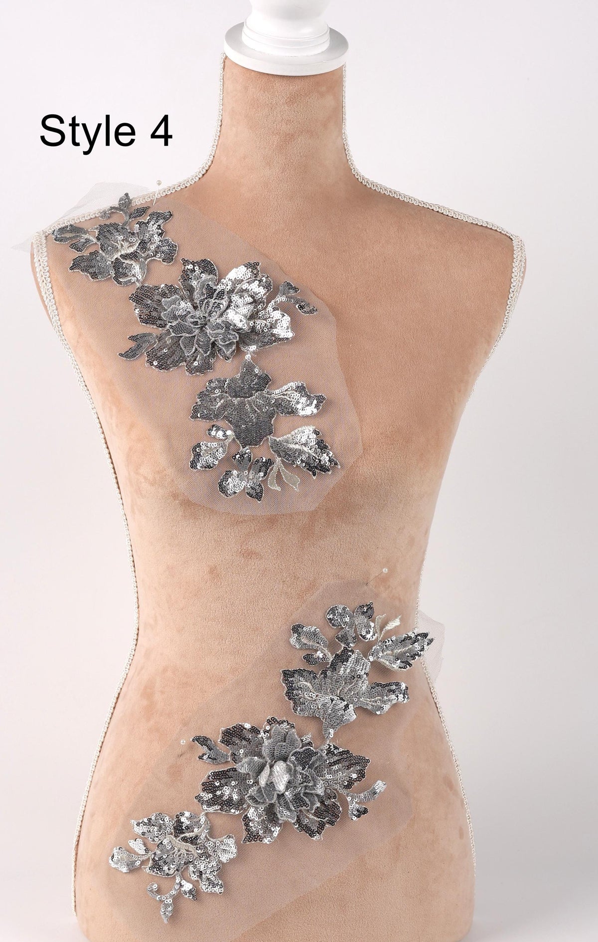 A mannequin with a beige body and silver floral embellishments on its torso.