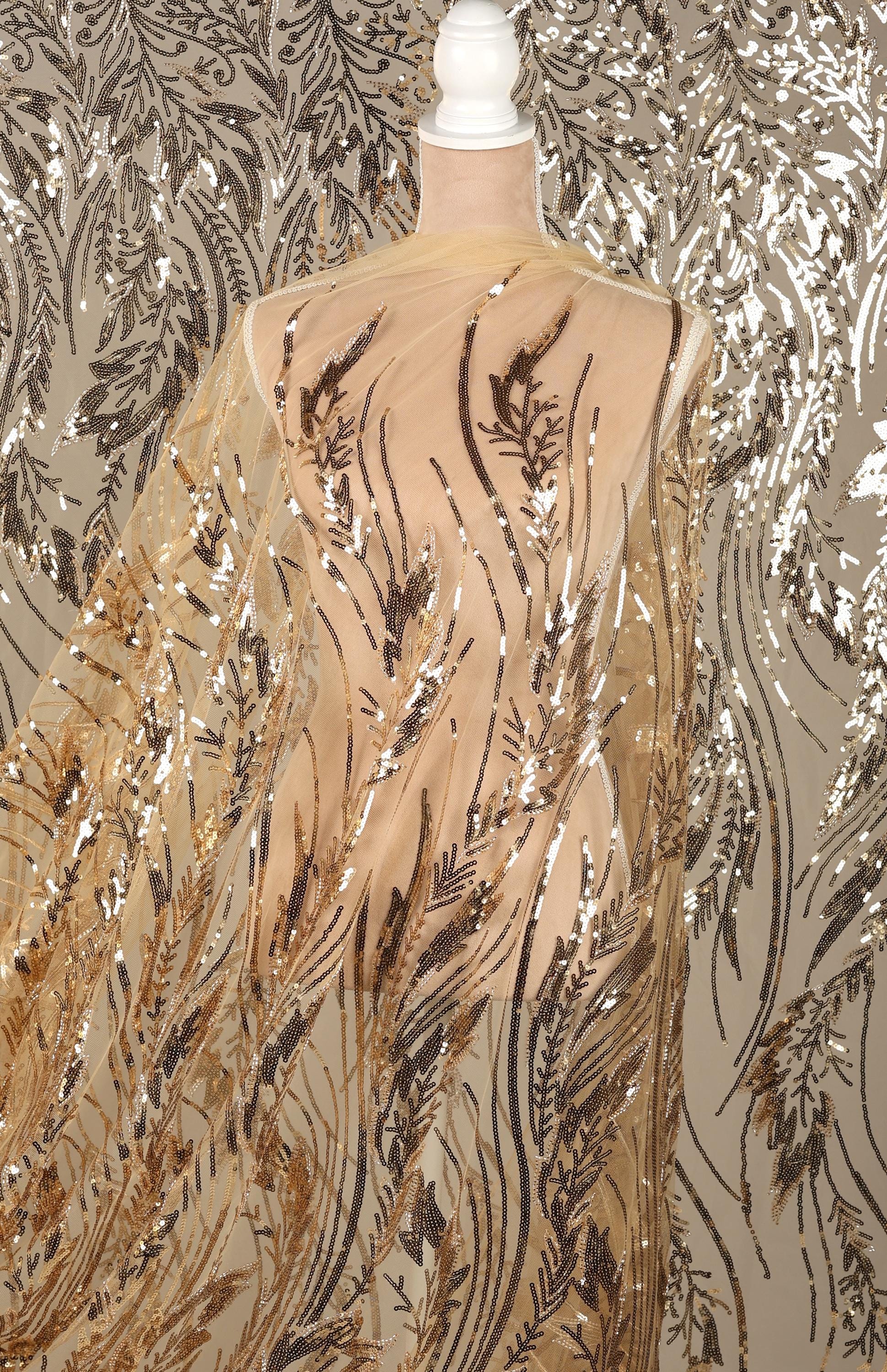 a mannequin wearing a sheer, gold-colored fabric with a floral pattern. The fabric appears to be made of sequin material and is draped over the mannequin's torso.