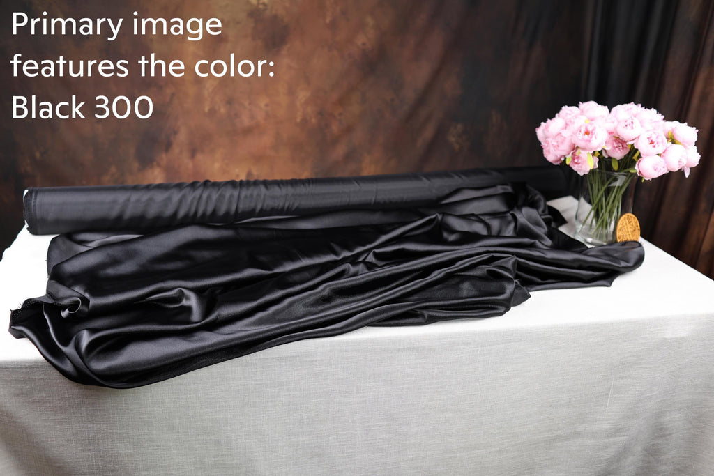 a black 300 fabric roll, a vase of pink flowers, and a white tablecloth.