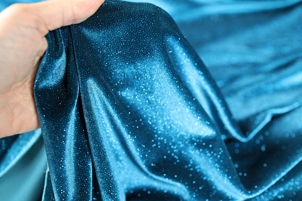 a hand holding a blue cloth with white spots
