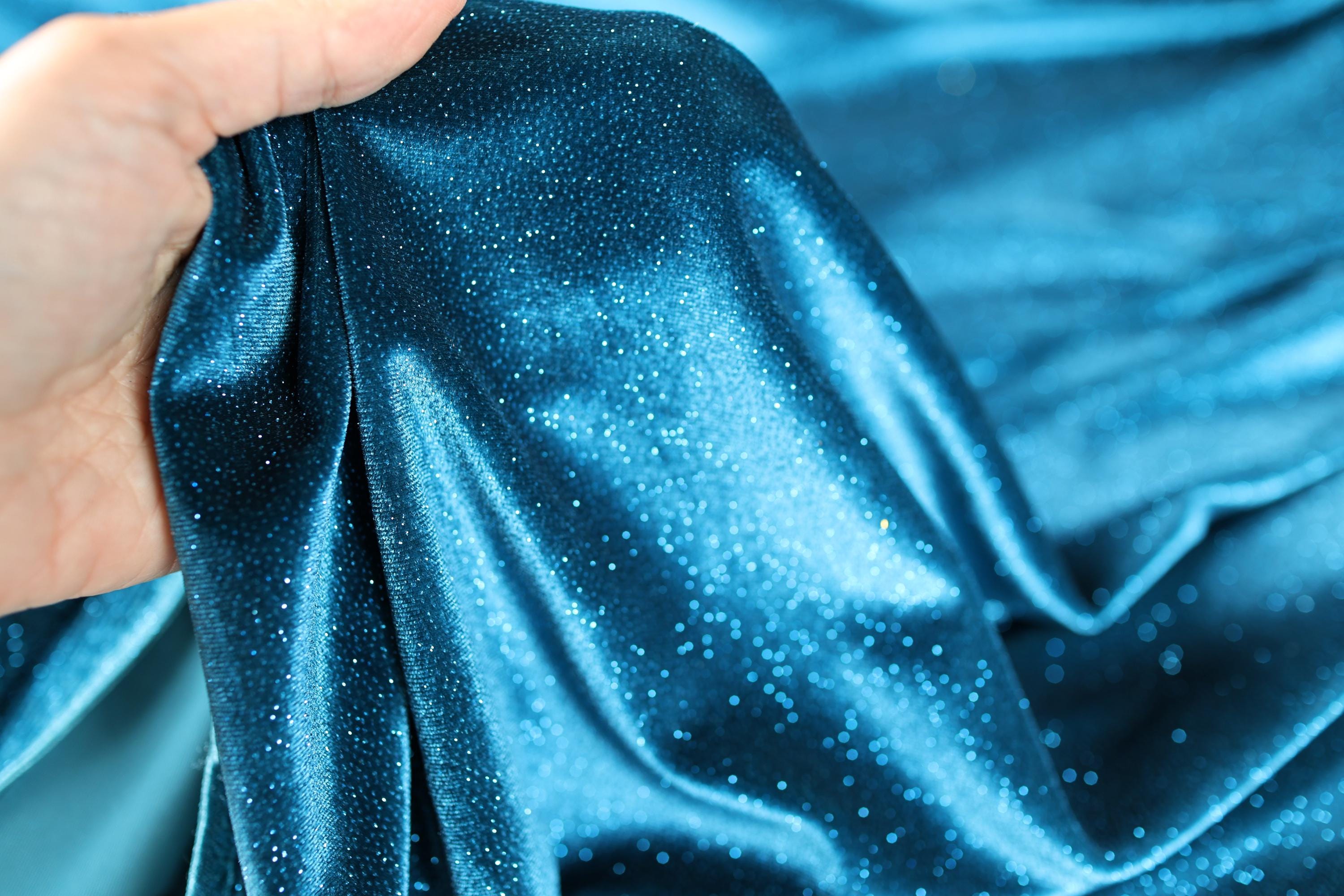 a hand holding a blue cloth with white spots