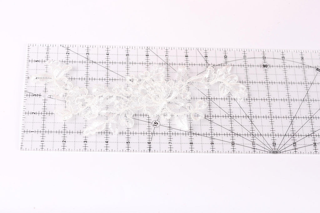 a clear ruler with a white lace pattern placed on it, indicating that it is being used for measuring or crafting purposes.