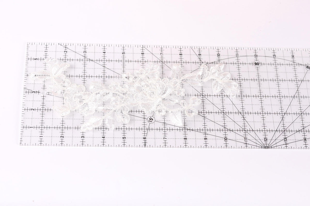 a clear ruler with a white lace pattern placed on it, indicating that it is being used for measuring or crafting purposes.
