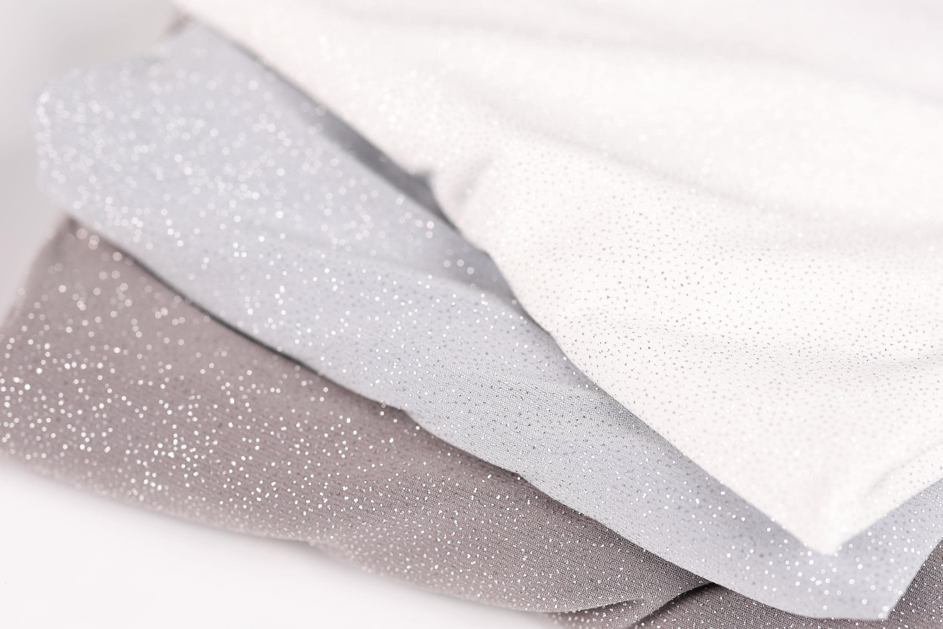 A close-up image of three fabric swatches, with the topmost one being white, the middle one being gray, and the bottom one being brown.