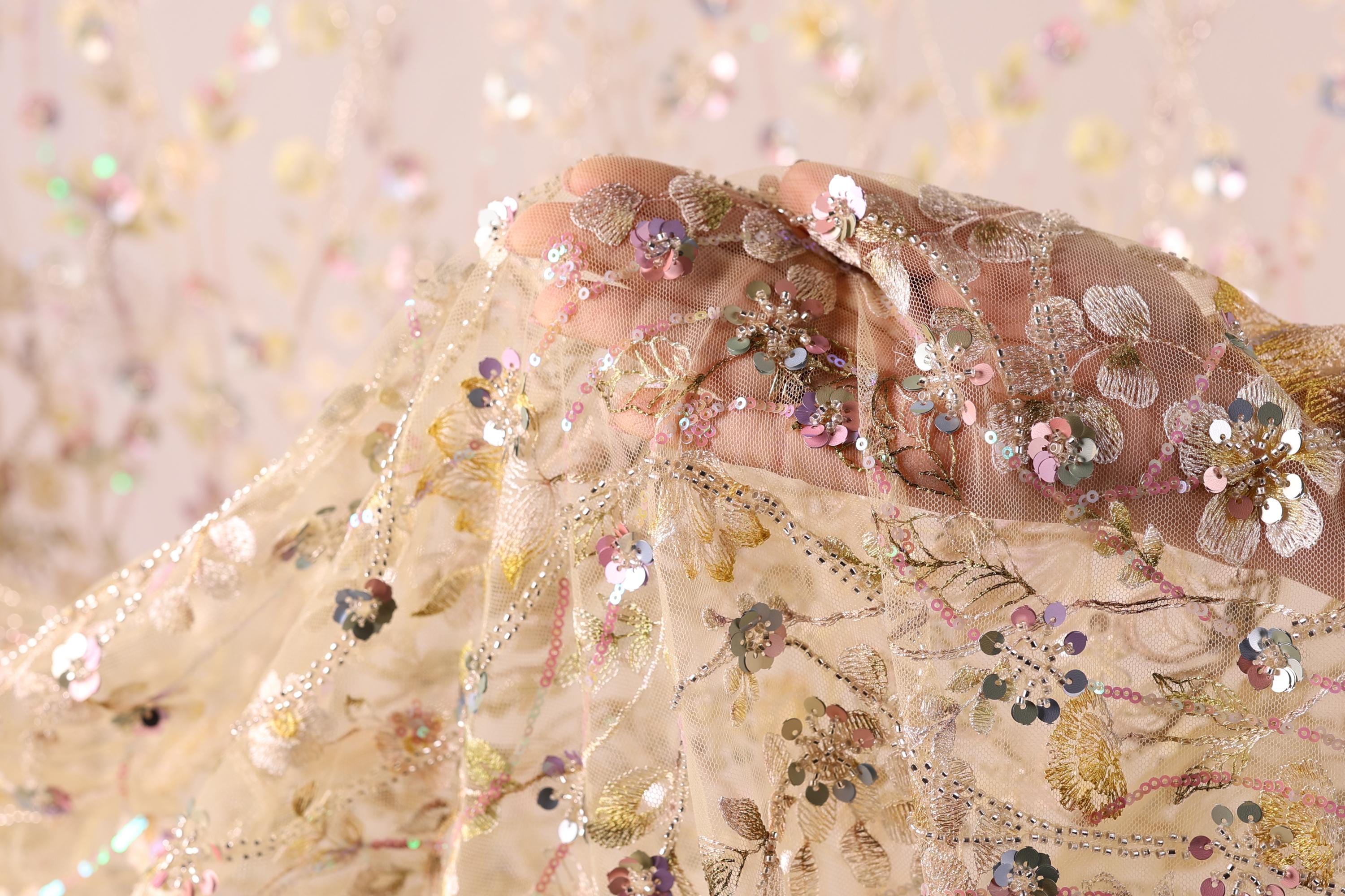 A close-up view of a delicate, intricately embroidered fabric with a floral pattern.