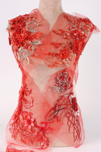 a red dress with intricate floral embroidery and a sheer, flowing design.