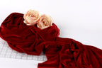 two pink roses resting on a crumpled red velvet fabric.