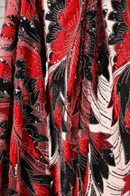 a close-up view of a fabric with a striking red and black floral pattern. The fabric appears to be made of a sheer material, with a mix of red, black, and white colors. The pattern is intricate and detailed, showcasing the craftsmanship of the fabric.