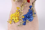 a close-up view of a beige fabric with a floral design, including yellow and blue flowers and leaves.
