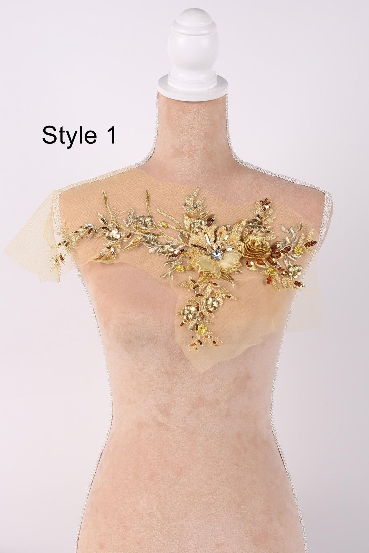A mannequin wearing a gold and beige floral embellishment on its shoulder.