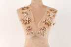 A mannequin with a beige dress featuring intricate gold and white floral embroidery on the shoulders.