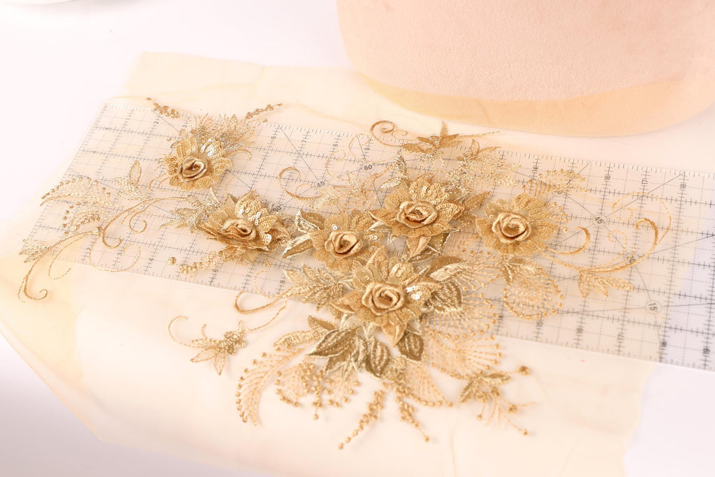 a close-up view of a delicate gold embroidered floral design on a piece of fabric.