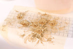 a close-up view of a delicate gold embroidered floral design on a piece of fabric.