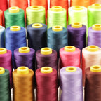 A close-up image of a collection of colorful spools of thread, with each spool featuring a yellow cap.