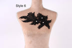 A mannequin with a decorative black lace piece on its bust, featuring a floral pattern with three small white flowers.