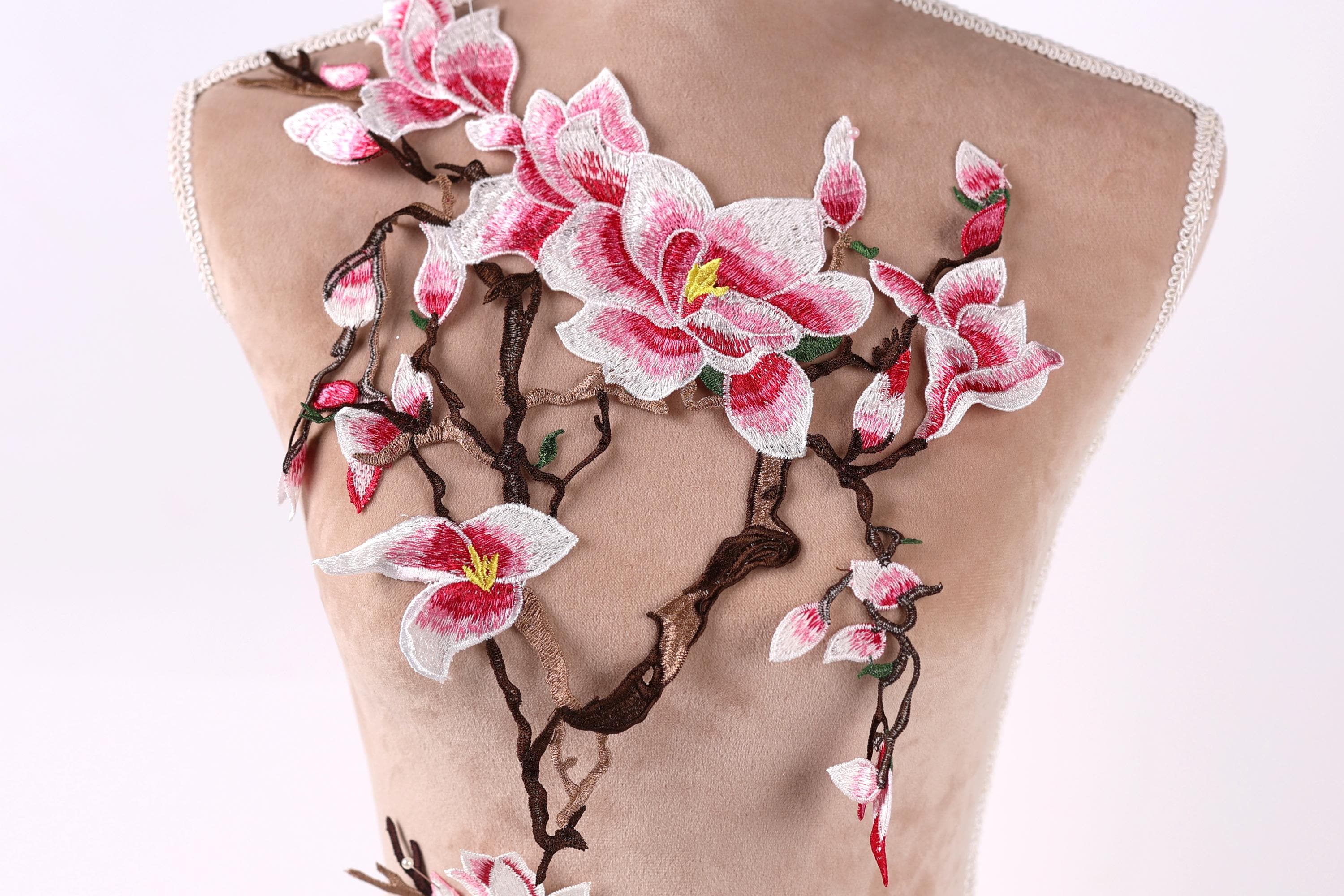 a mannequin with a floral design on its back. The design consists of pink and white flowers with green leaves, creating a delicate and elegant appearance.