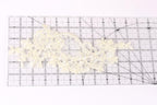 a piece of white lace with intricate floral patterns placed on a transparent ruler.