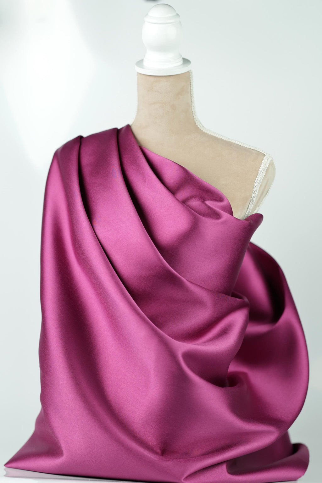A mannequin is wearing a vibrant purple satin fabric draped over its body.