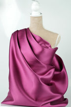 A mannequin is wearing a vibrant purple satin fabric draped over its body.