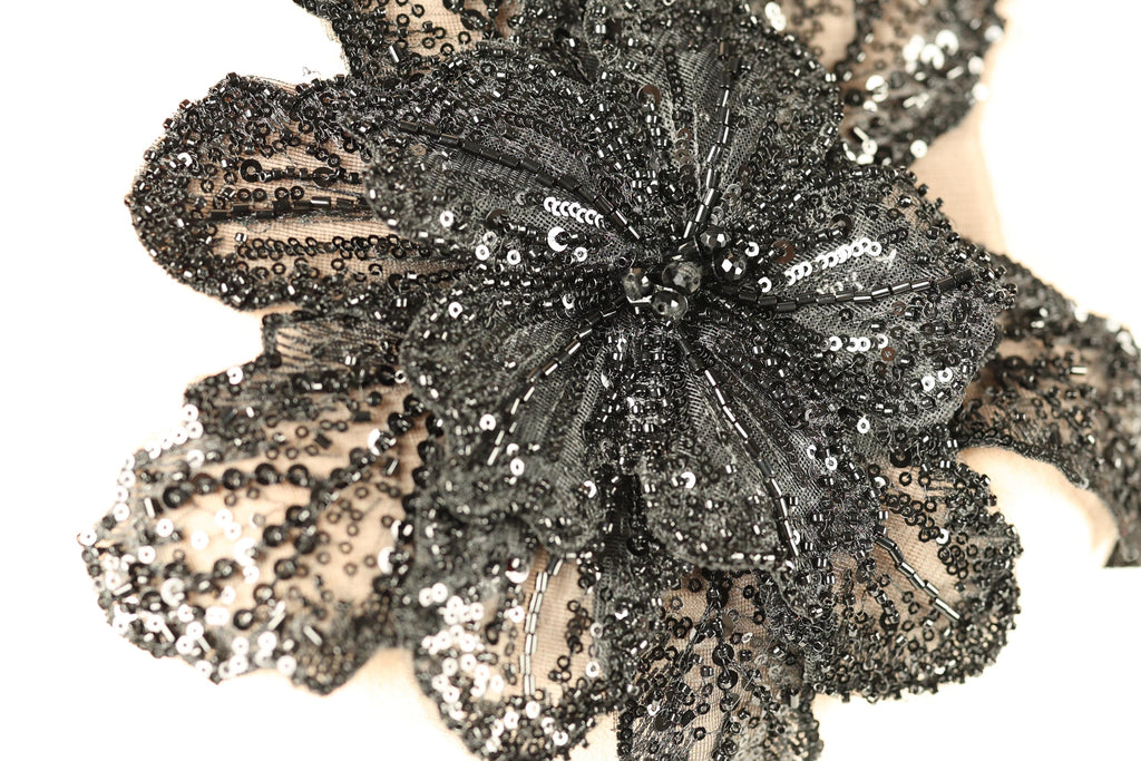 A close-up image of a black sequin flower-shaped object with intricate details and patterns.