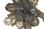 A close-up image of a black sequin flower-shaped object with intricate details and patterns.
