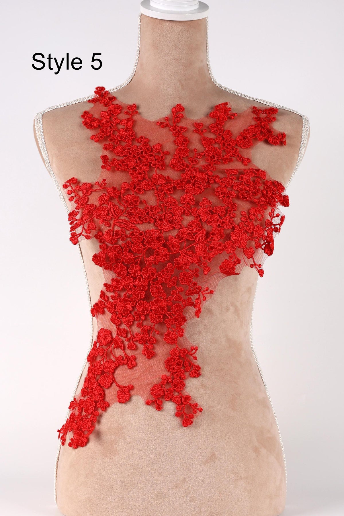 A mannequin wearing a red floral lace dress with a floral pattern on the bodice.