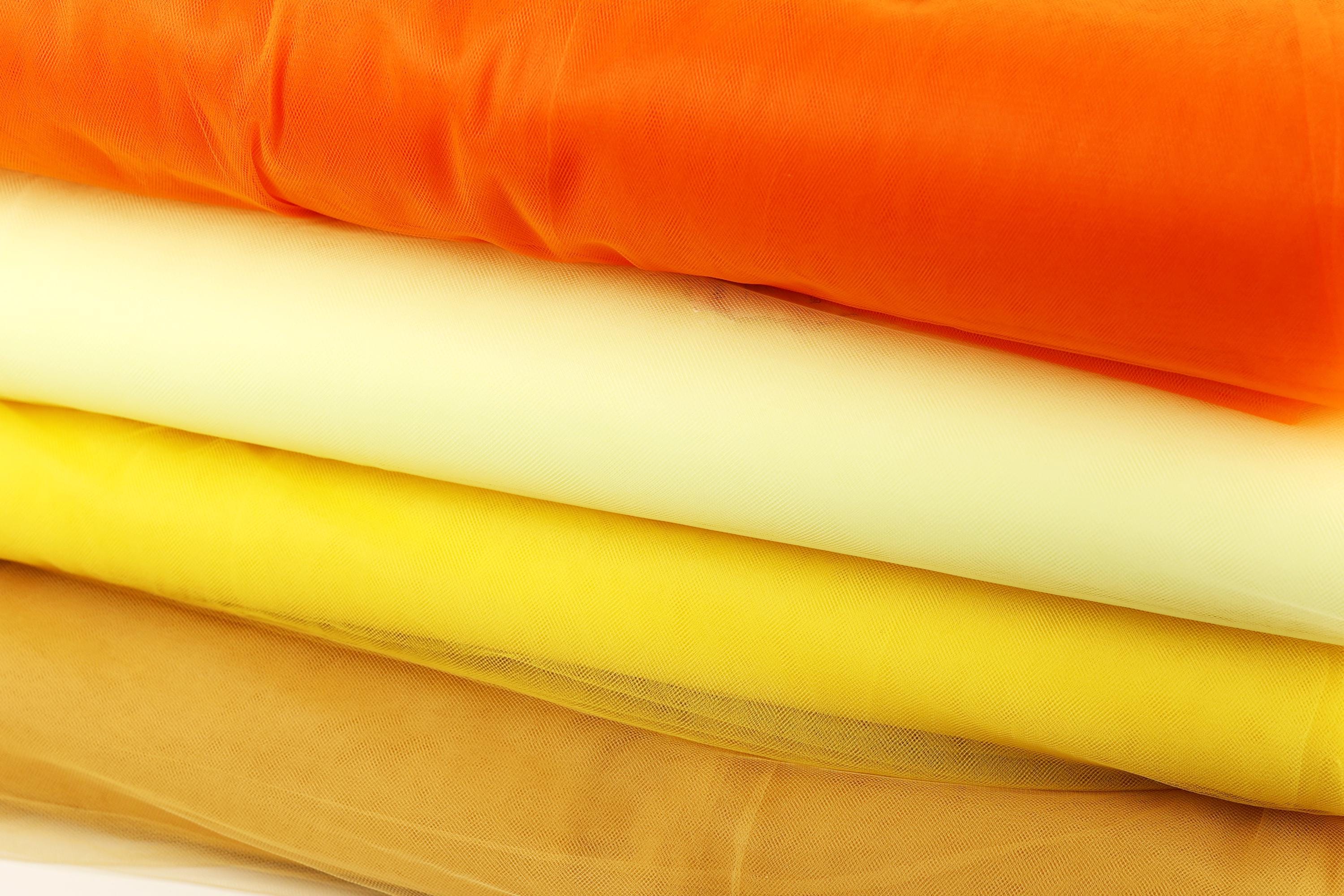 A stack of colorful fabric swatches in various shades of orange, yellow, and white.