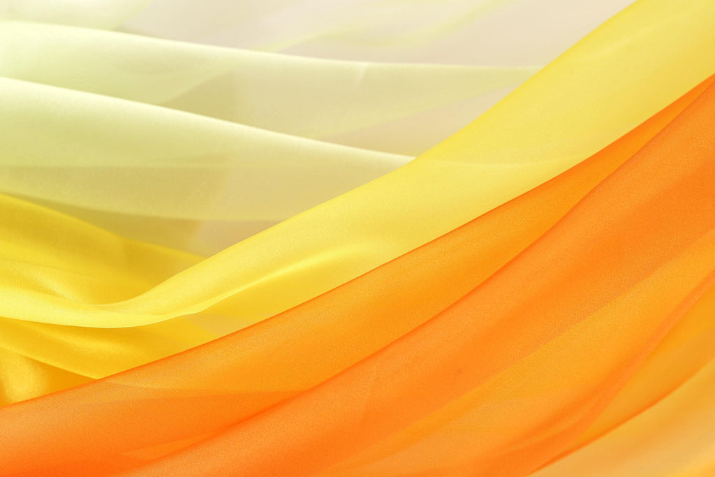The image is a close-up of a fabric with a vibrant yellow and orange gradient, creating a visually striking and warm color scheme.