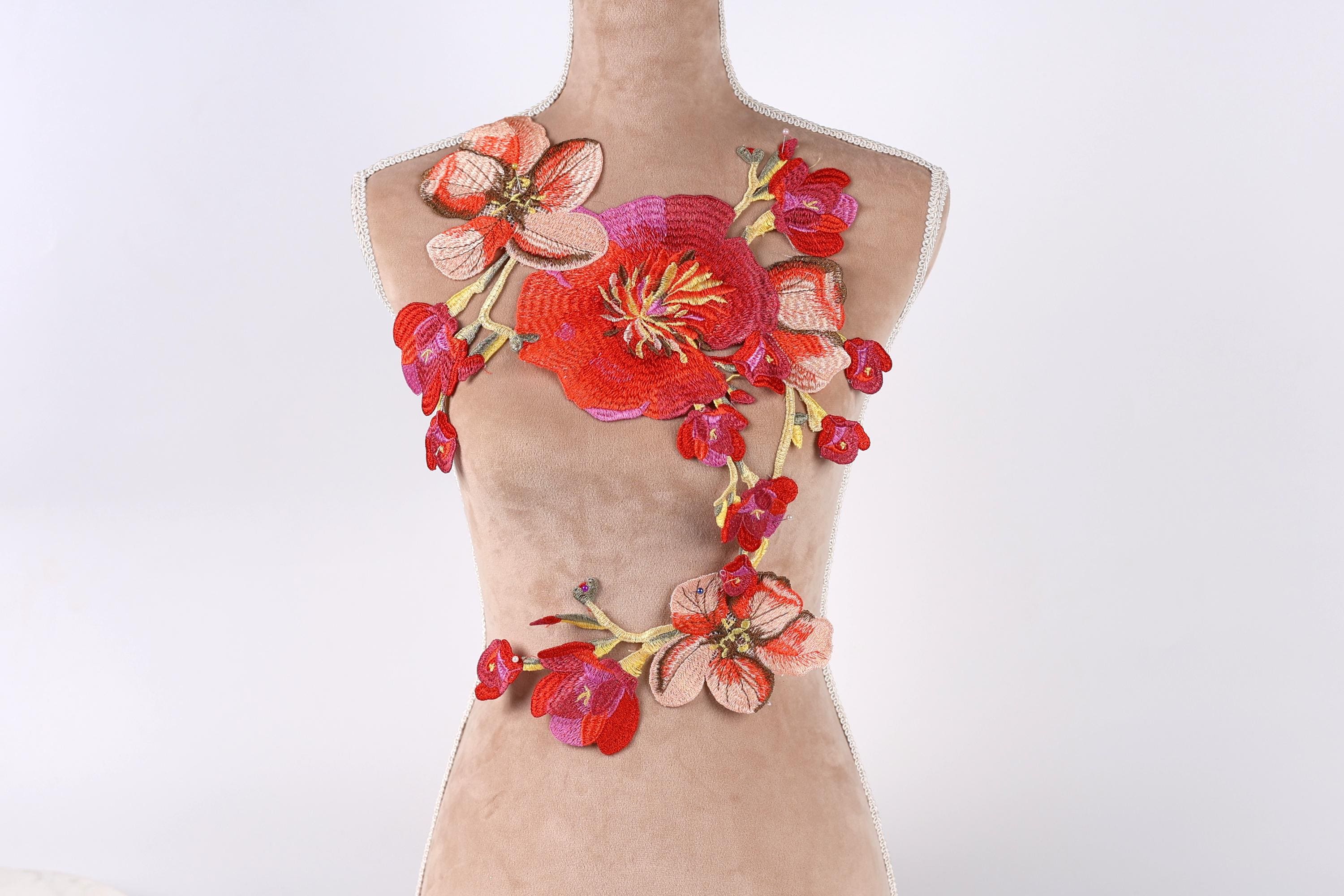A mannequin wearing a dress with a floral embroidered design on the chest area.