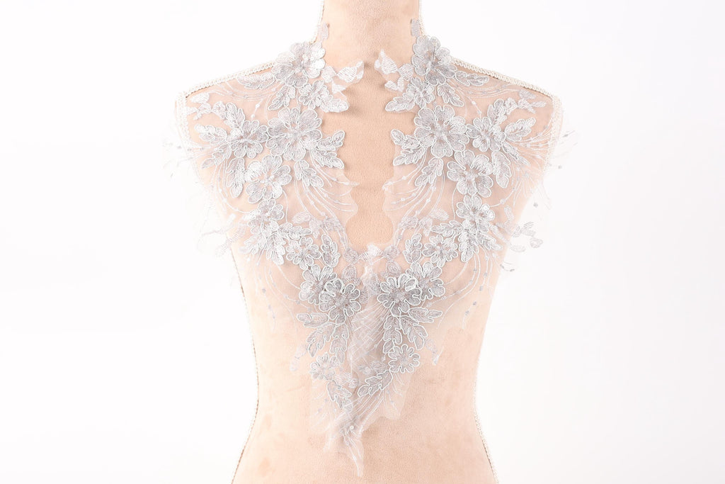 A mannequin wearing a delicate, lace-like collar with intricate floral patterns.