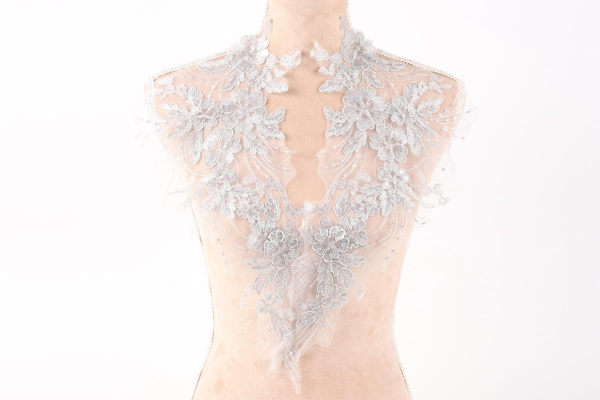 A mannequin wearing a delicate, lace-like collar with intricate floral patterns.