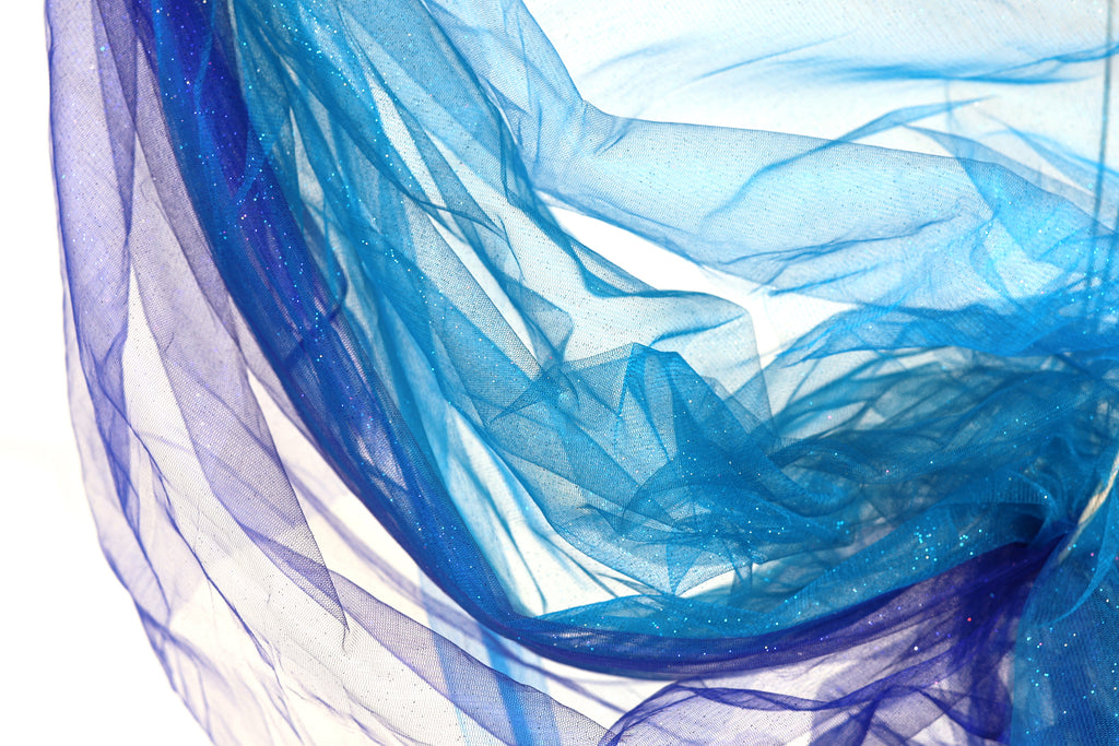 The image is a close-up of a piece of blue and purple fabric, with the fabric appearing to be made of sheer material. The fabric has a flowing, draped appearance, and the colors are vibrant and eye-catching.