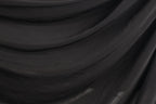 The image is a close-up of a black fabric, possibly a piece of clothing or a textile. The fabric appears to be wrinkled and has a textured surface, giving it a somewhat rough appearance.
