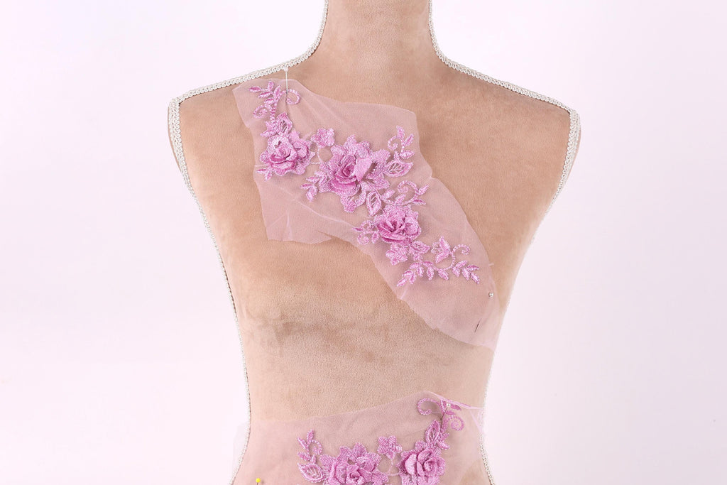 A mannequin wearing a pink dress with a floral pattern on the shoulder and skirt.