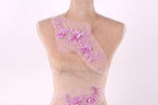 A mannequin wearing a pink dress with a floral pattern on the shoulder and skirt.